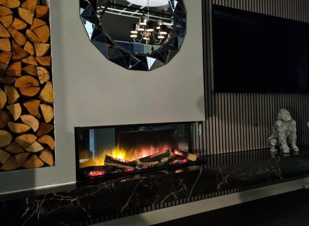 Modern fireplace with glowing logs and a mirror above, set in a sleek living space.