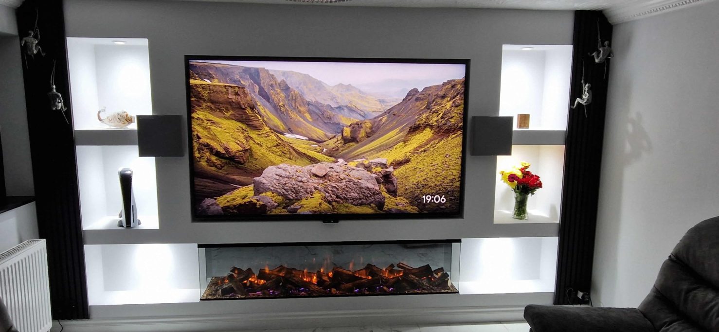Modern living room with a large TV, decorative shelves and British Fires 1900 with deluxe real logs