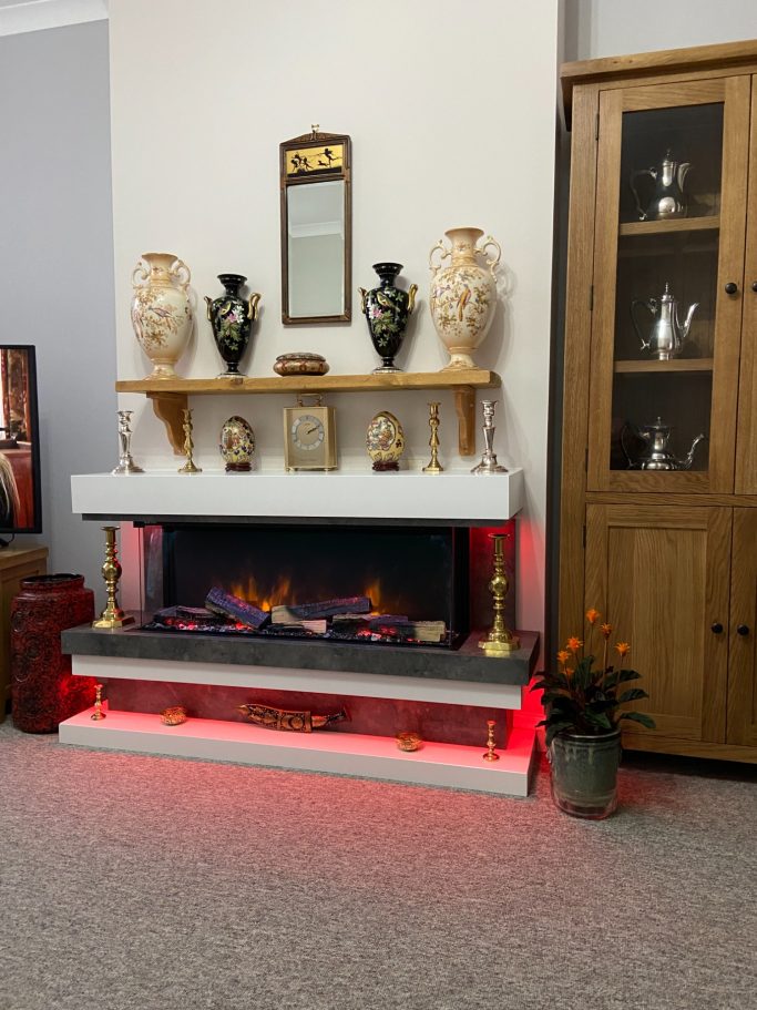 Modern living room featuring a decorative fireplace with LED lights, vases, and a wooden cabinet.