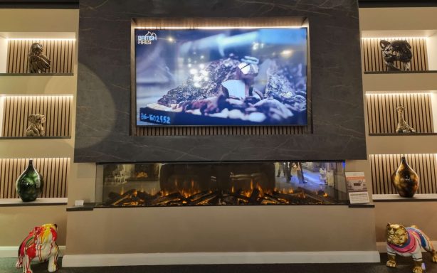 A modern fireplace beneath a large TV with decorative objects around.