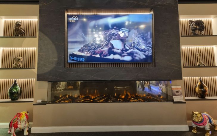 A modern lounge with a large television above a stylish British Fires New Forest 2400 and decorative shelves.