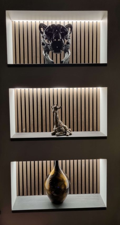 Three decorative shelves with sculptures lit with LEDs, in our media wall on display