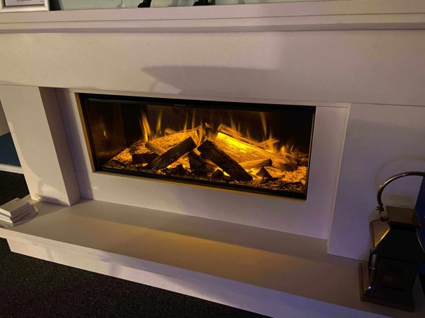 A modern fireplace with glowing flames and logs, framed by a sleek white mantle.