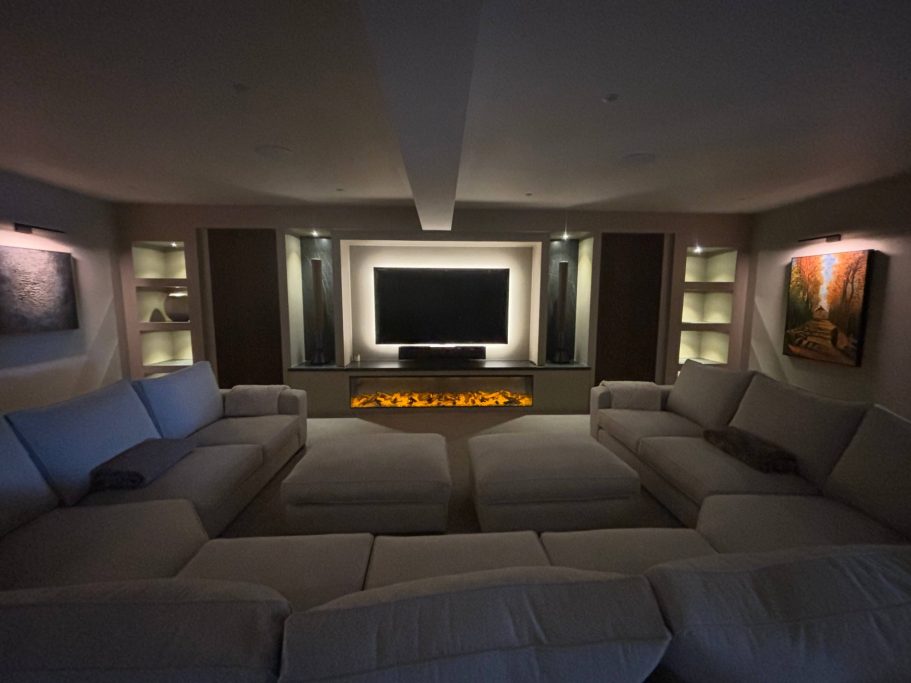 A modern living room with a large sectional sofa and a wall-mounted TV, softly lit.