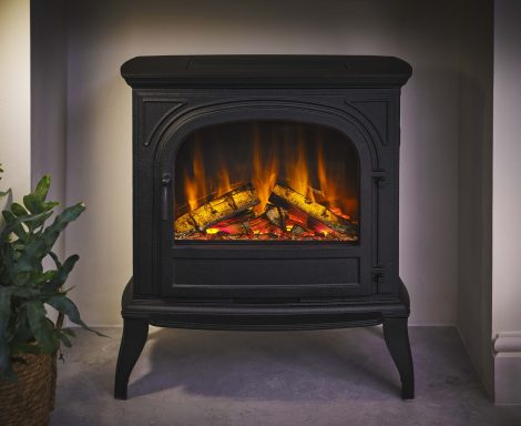 Black electric stove with a glowing fire and logs inside, set against a plain backdrop.