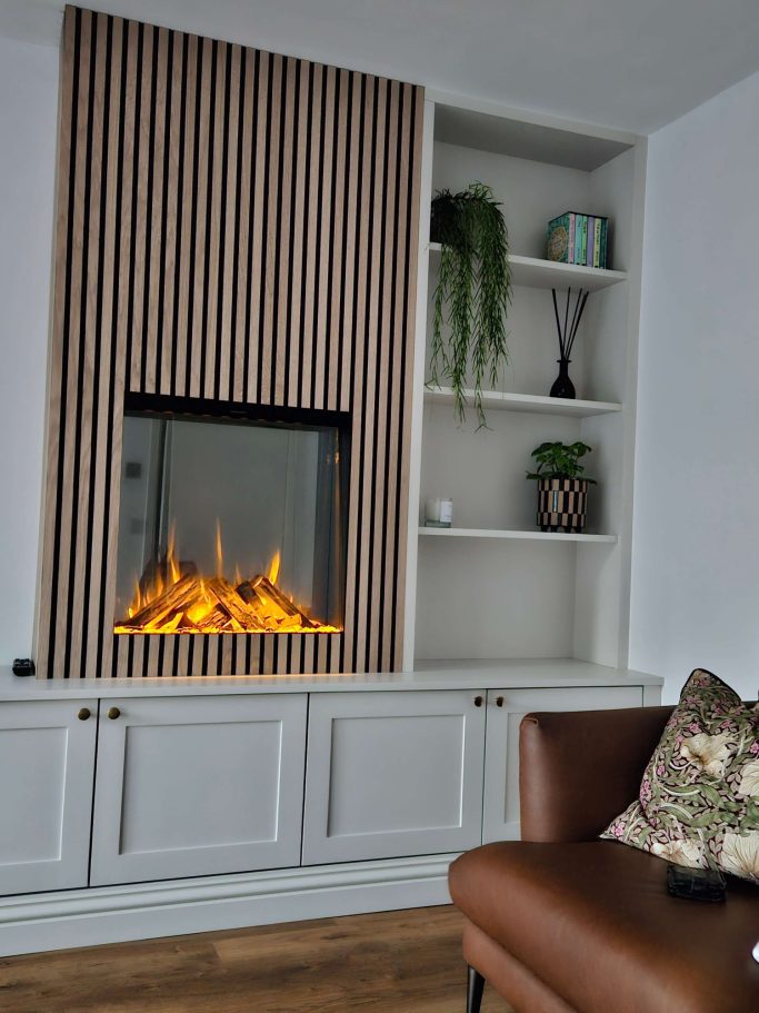 A modern living room featuring a vertical fireplace and shelving with plants and decor.
