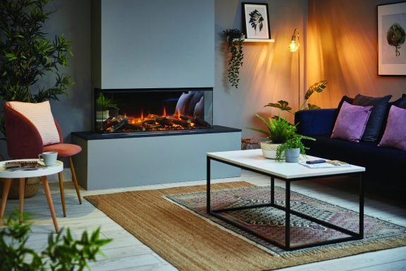Modern living room with a 1200 fireplace, plants, and a coffee table, featuring warm lighting.