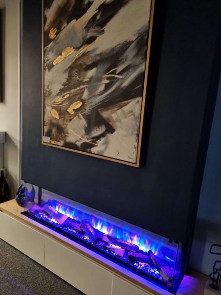 Flamerite E-FX 1500 fire with blue pink flames and abstract artwork above it.