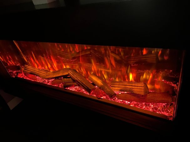 Flame effect with logs and glowing red embers in a dark setting.