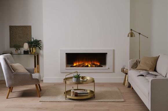 A modern living room with an electric recessed fireplace, sofa, armchair, and decorative table.